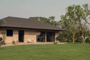 A modern house with a sloping roof and large window, surrounded by a well-maintained grassy area