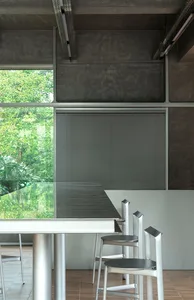 Modern dining room with a metal table, leather chairs, and a large window allowing natural light to fill the space