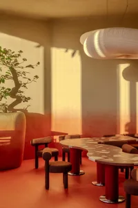 Cozy dining area with brown tables, modern chairs, and potted plants, warm lighting creating a welcoming atmosphere