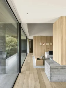 Open modern living space with a wooden floor, natural light, and various furniture and decorative items