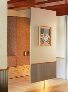 A warm and inviting hallway with a yellow wall, wooden floor, and a painting of a dining table with food on it
