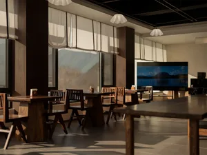 A modern restaurant with wooden tables and chairs, well-lit with natural light from windows, perfect for a relaxing meal or gathering