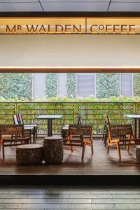 A modern restaurant with a wooden floor, multiple seating options, and soft lighting creating a cozy atmosphere