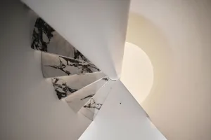 A modern staircase with marble steps and a white wall, set in a bright and clean room with natural light