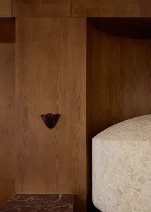 Small, dark room with wooden walls, a brown wooden door, and a wooden floor, lit dimly