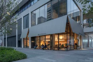 A modern cafe with a glass front, comfortable seating, and natural light, featuring chairs and dining tables