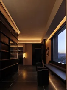 A dimly lit room with a black bench near a window and a bar in the center, featuring a black and white color scheme and sleek, contemporary design