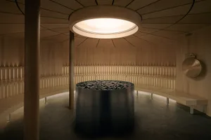 A modern lobby with a large metal vase in the center, a wooden floor, and dim lighting creating a calm atmosphere