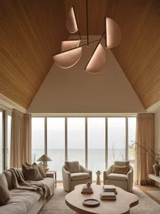 Bright and welcoming living room with a large window, a couch, a chair, and a dining table, surrounded by modern furniture and natural light