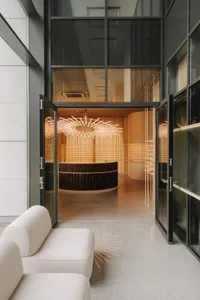 A modern living and dining space with a large window, a couch, and a dining table, bathed in natural light
