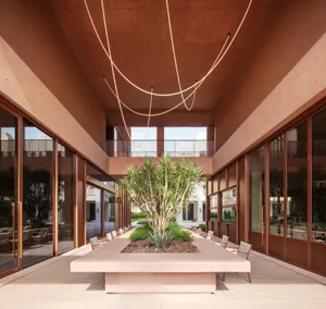 A modern dining space with a large table, chairs, a potted plant, and a hanging rope, set in a well-lit and inviting atmosphere