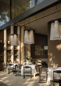 A modern restaurant interior with wooden furniture, white tablecloths, and a warm atmosphere created by well-placed lighting