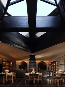 Bright and inviting restaurant with a large dining area, natural light from a skylight, and modern wood and glass materials
