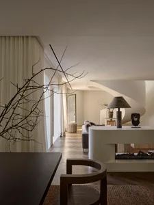 Cozy living room with a fireplace, wood furniture, and white walls, lit by natural sunlight