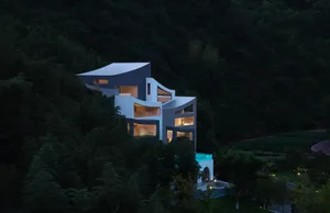 A serene and picturesque modern house with a swimming pool, surrounded by trees and mountains, featuring a mix of white and gray elements