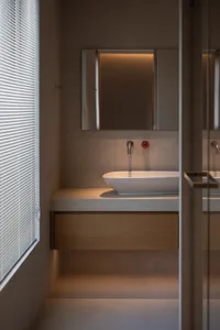 A modern bathroom with a white bathtub and wooden accent, well-lit and clean, with a sink to the right of the bathtub