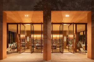 A modern study with a large bookshelf, well-lit by natural and artificial light, creating a cozy and intellectual atmosphere