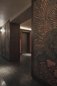 A dimly lit hallway with a wooden door featuring intricate design, set against a plain background