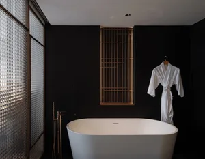 Modern bathroom with a white clawfoot tub, toilet, and sink in a dimly lit space