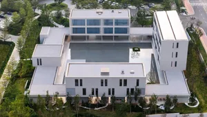 A large white building with a pool in the center, surrounded by a deck, in a modern architectural style with a sense of luxury and sophistication