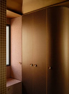 Bathroom with a pink door, brown cabinet, and natural light from a window