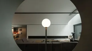 溫馨的現代客廳，擺設著沙發、椅子和燈泡，背景為白牆和木家具，照著柔和的燈光