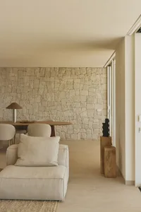 Cozy living room with a stone accent wall, a couch, a chair, and a dining table, creating a comfortable and inviting atmosphere