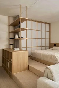 Cozy bedroom with a bed, bookshelf, and wooden floor, well-lit and inviting