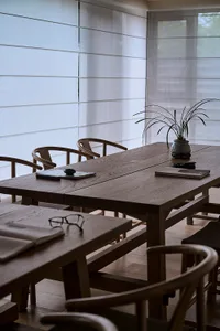 A warm and inviting dining area with a wooden table and chairs, surrounded by a potted plant and natural light