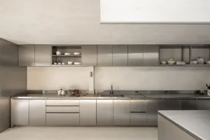 Modern kitchen with stainless steel appliances, metal countertops, and a dining table, featuring a sleek and contemporary design
