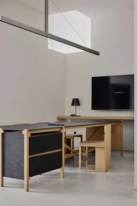 Cozy home office with a wooden desk, flat screen TV, and computer setup, surrounded by a few personal items