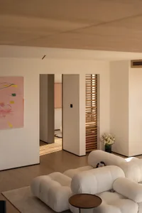 A well-lit living room with a white couch and chair, surrounded by a clean and simple space
