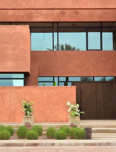 A modern red building with a large window, concrete exterior, and natural light pouring in