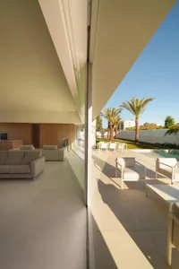 Comfortable living space with a glass door leading to a patio, featuring a couch, chair, and dining table, with natural light and neutral colors