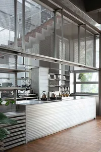 Modern kitchen with a stainless steel counter, sink, refrigerator, and microwave, featuring minimalist and functional design