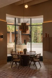 A modern dining room with a table and chairs, surrounded by vases, and a large window allowing natural light to enter