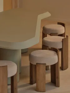 Modern kitchen with a white dining table, brown stools, and a chair, featuring a counter with a sink and warm soft lighting