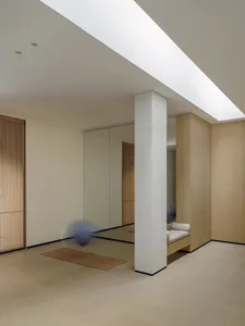 A dimly lit bedroom with a white floor, a bed in the corner, and a blue ball on the floor, creating a cozy atmosphere