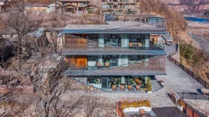 Modern multi-story building with a curved glass wall, concrete exterior, and interior furniture and decor