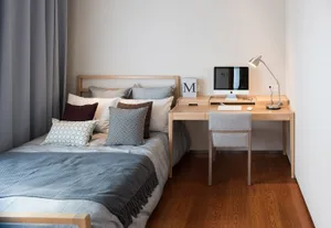 Cozy bedroom with a bed, desk, and chair, featuring a wooden floor and dim lighting