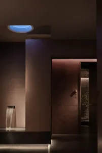 Bathroom with a brown color scheme, stone walls, and a tile floor, featuring a shower on the left and a toilet on the right in a dimly lit space