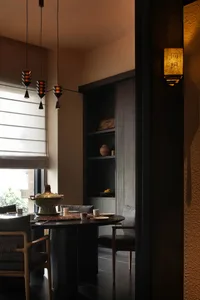一間充滿柔和燈光的餐廳餐桌環境，餐桌上擺放著花瓶、咖啡杯和碗盤，周圍還有舒適的家具