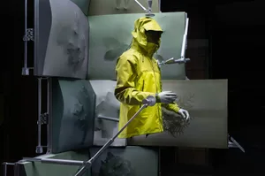 A mannequin in a yellow raincoat stands in front of a green wall in a store or display area, creating a bright and cheerful scene