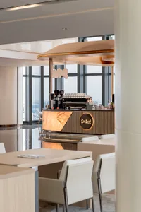 A modern coffee shop with a marble counter, coffee machine, and soft warm lighting, creating a comfortable and inviting atmosphere