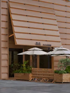 Photograph of a traditional building with a brown wooden exterior, featuring a large wooden awning and a wooden bench in front of it