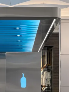 Dimly lit modern closet with a blue ceiling, blue-tiled roof, and wooden floor, filled with neatly arranged clothing items