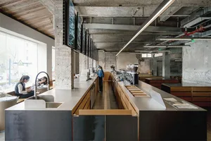 A bustling restaurant with a stainless steel counter, modern industrial design, and a lively atmosphere