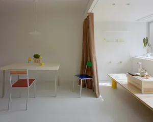 一間現代用餐區域的白色桌子、色彩繽紛的椅子和掛帷幔，配上溫和且柔和的照明