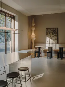 Well-lit contemporary bar with a counter, stools, and decorative items, set in a restaurant or bar space with soft and warm lighting
