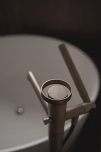 A modern bathroom with a white sink and a wooden faucet, set in a dimly lit space